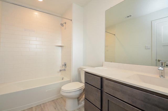 bathroom with toilet, wood finished floors, vanity, visible vents, and bathing tub / shower combination