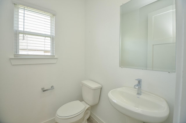 bathroom featuring toilet, baseboards, and a sink