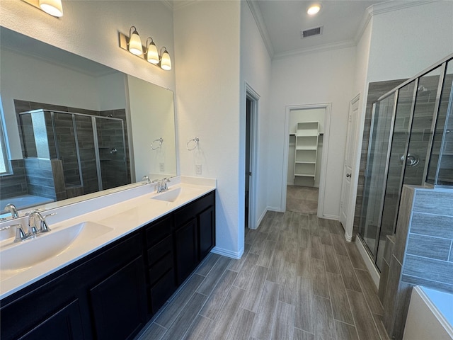 bathroom with a shower stall, crown molding, visible vents, and a sink