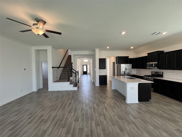 kitchen featuring dark cabinets, a sink, visible vents, open floor plan, and appliances with stainless steel finishes