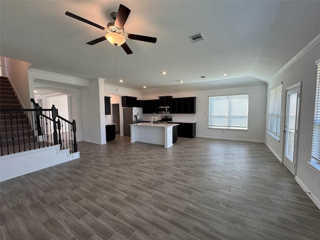 kitchen featuring open floor plan, a kitchen island with sink, visible vents, and dark cabinets