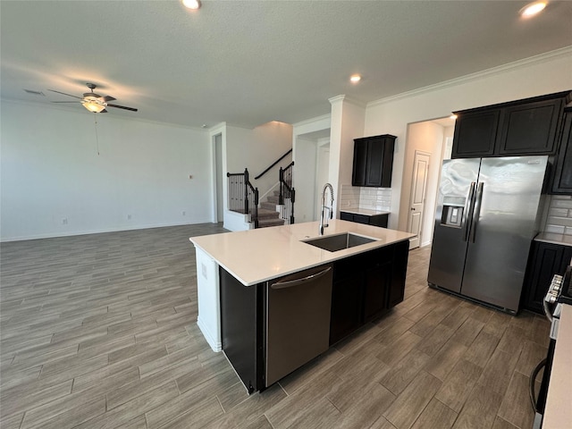 kitchen featuring appliances with stainless steel finishes, wood finish floors, a sink, and a center island with sink