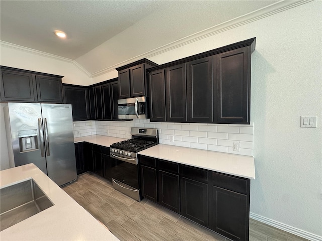 kitchen with lofted ceiling, light wood-style floors, stainless steel appliances, and backsplash