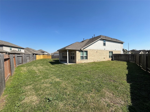 back of property with brick siding, a yard, and a fenced backyard