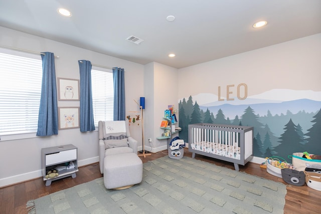 bedroom with recessed lighting, a crib, baseboards, and wood finished floors