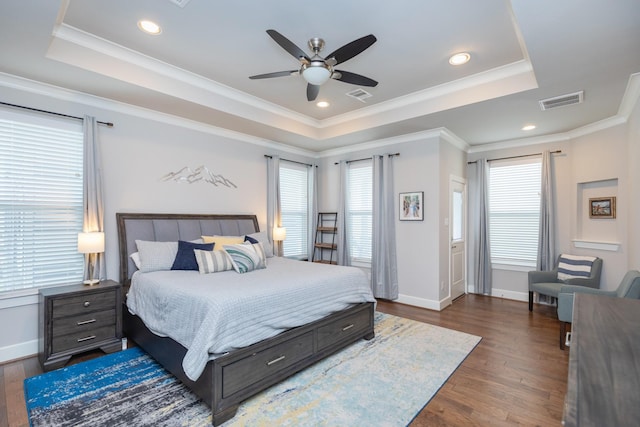 bedroom with dark wood-style floors, visible vents, and a raised ceiling