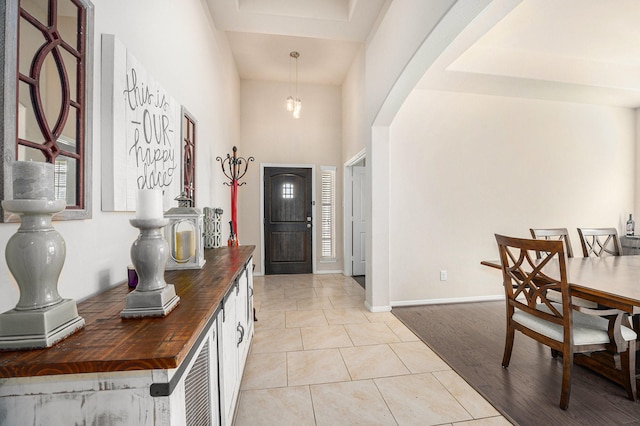 foyer entrance with arched walkways, light tile patterned floors, and baseboards