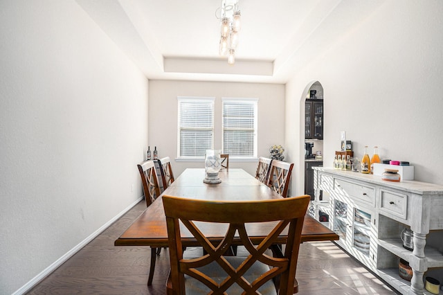 dining room featuring dark wood-style floors, baseboards, and a raised ceiling