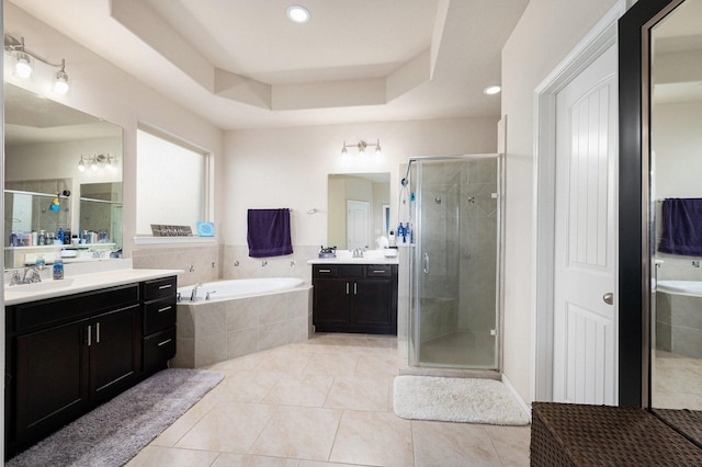 bathroom featuring a garden tub, a shower stall, a tray ceiling, and a sink