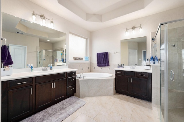 full bath with a bath, a stall shower, a tray ceiling, and a sink