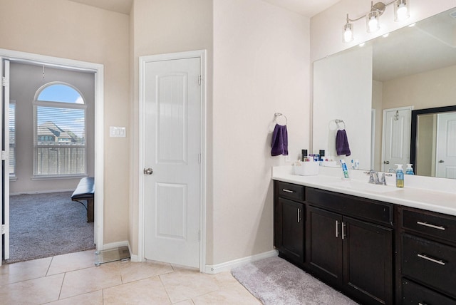 bathroom featuring tile patterned floors, vanity, baseboards, and ensuite bathroom