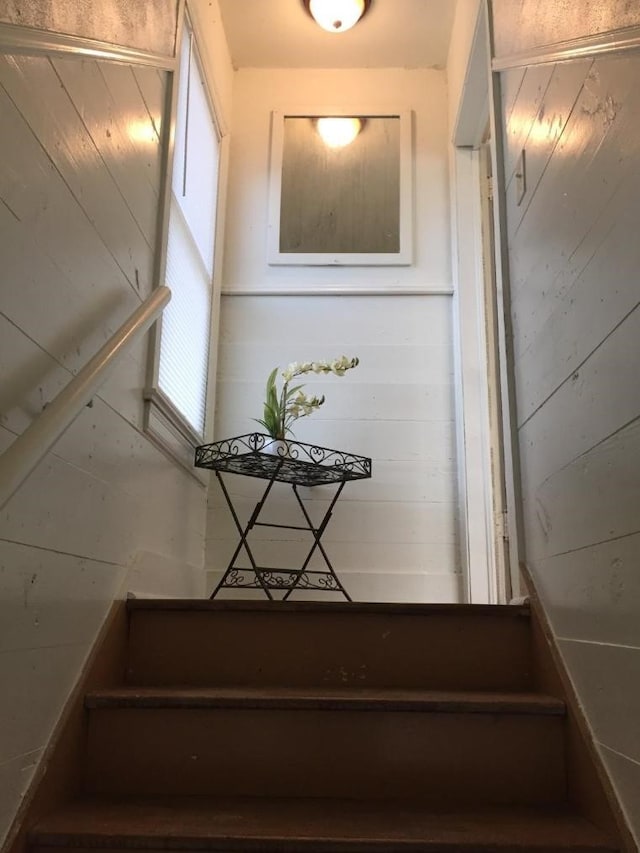 stairway featuring wood walls