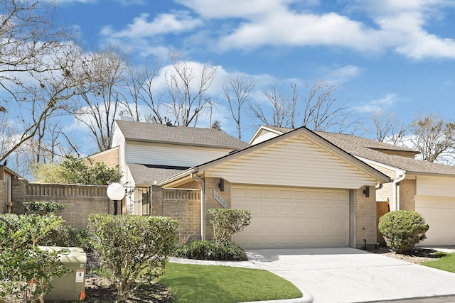 view of front of house featuring an attached garage, driveway, fence, and brick siding