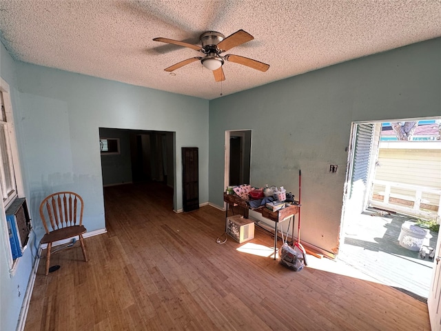 interior space with a textured ceiling, wood finished floors, a ceiling fan, and baseboards