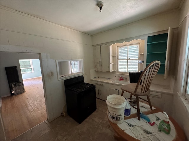 kitchen with light countertops, black gas stove, plenty of natural light, and white cabinetry