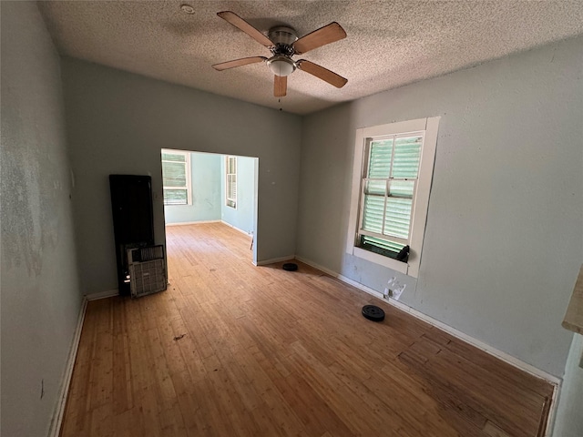 interior space featuring ceiling fan, light wood-style flooring, baseboards, and a textured ceiling