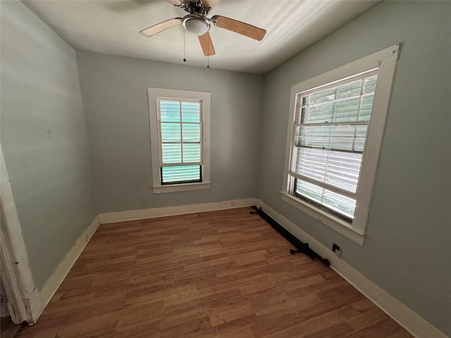 empty room featuring dark wood-style floors, ceiling fan, and baseboards