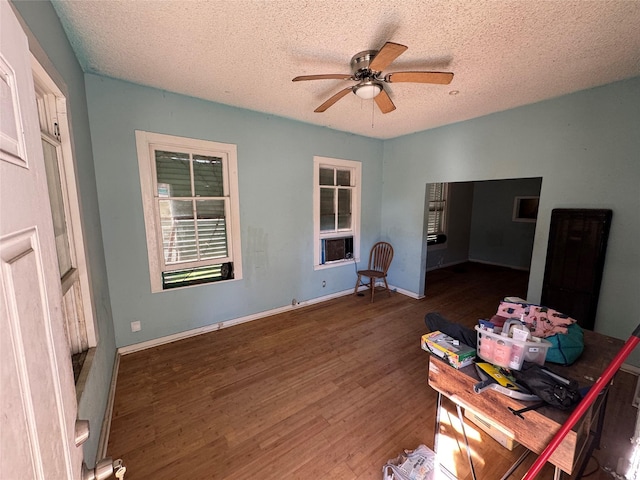 interior space featuring a textured ceiling, baseboards, dark wood finished floors, and a ceiling fan