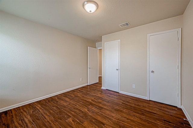 unfurnished bedroom with baseboards, visible vents, and dark wood-style flooring