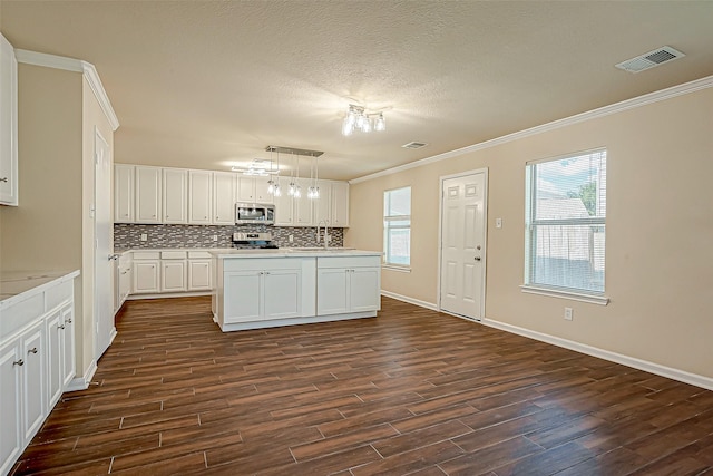 kitchen featuring stainless steel appliances, light countertops, hanging light fixtures, and visible vents