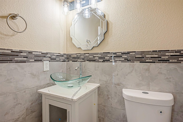 bathroom with toilet, a textured wall, and vanity