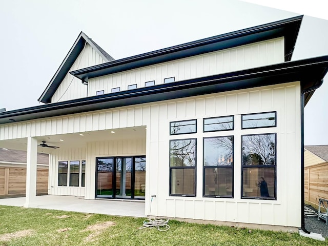 back of property featuring a ceiling fan, fence, a yard, a patio area, and board and batten siding