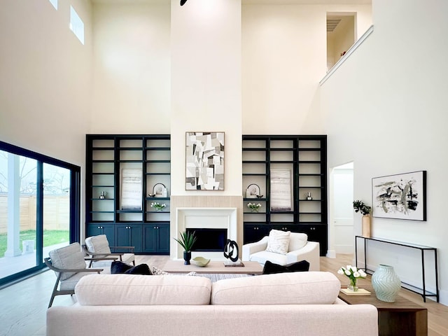 living area featuring a high ceiling, a fireplace, and light wood-style floors