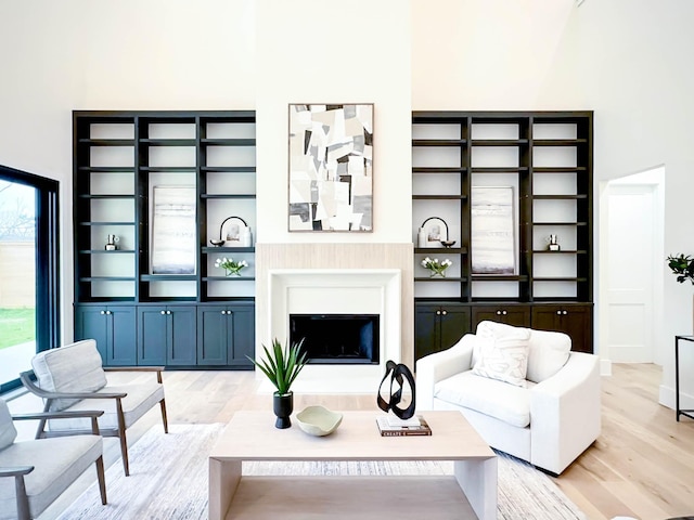 living area featuring light wood finished floors, a fireplace, and a high ceiling