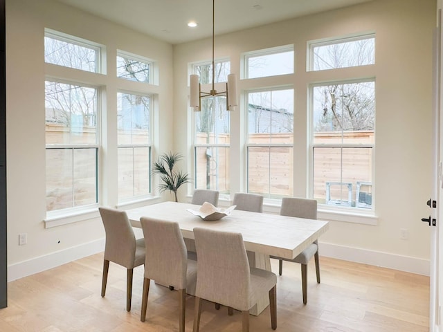 dining area with baseboards, light wood finished floors, and a healthy amount of sunlight