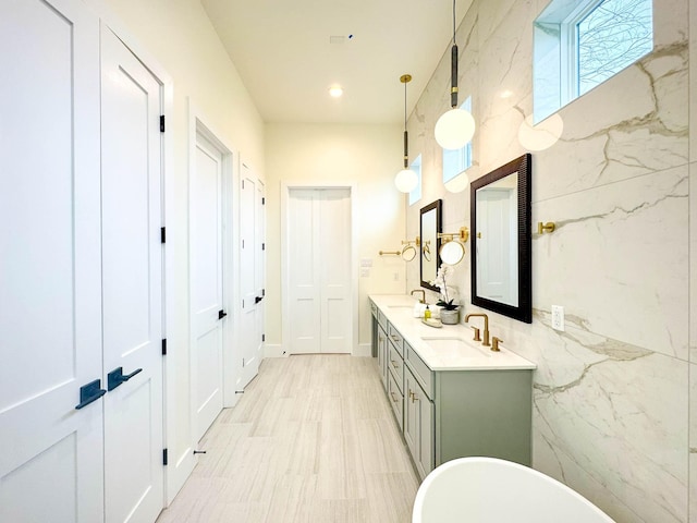 bathroom with double vanity, a freestanding tub, a sink, and recessed lighting