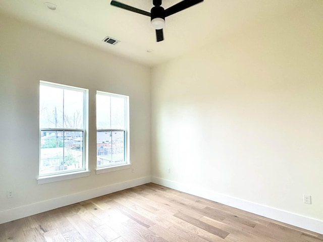 spare room featuring baseboards, a ceiling fan, visible vents, and light wood-style floors