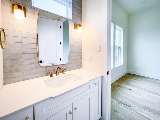 bathroom with baseboards, decorative backsplash, wood finished floors, and vanity