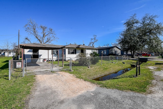 view of front of home with dirt driveway, a fenced front yard, a gate, and a front lawn