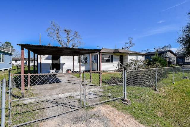 view of front facade with driveway, a fenced front yard, a gate, a carport, and a front yard