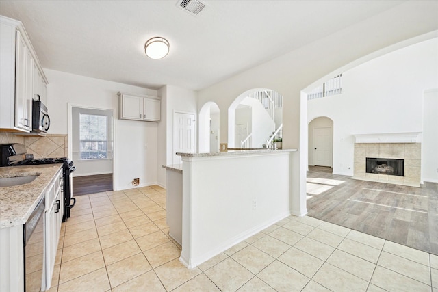 kitchen with light tile patterned floors, visible vents, light stone countertops, stainless steel appliances, and white cabinetry