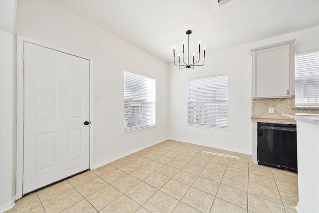 unfurnished dining area featuring an inviting chandelier, light tile patterned floors, and baseboards