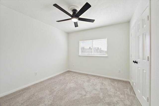 unfurnished bedroom with light carpet, a ceiling fan, and baseboards