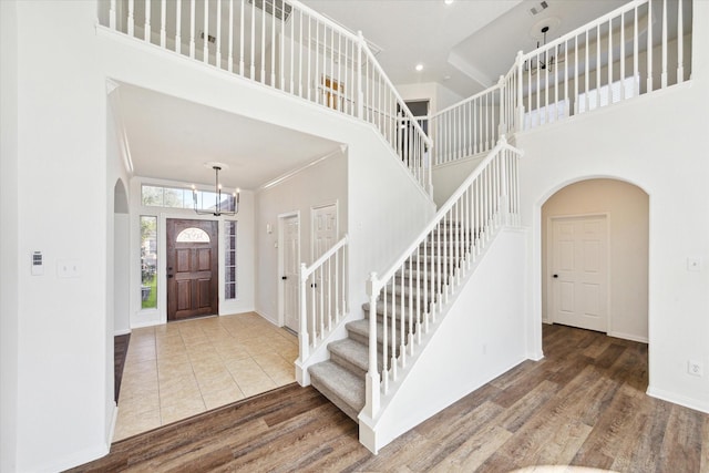 entryway featuring arched walkways, a towering ceiling, and wood finished floors