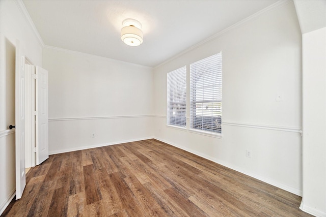 spare room with ornamental molding, dark wood-style flooring, and baseboards