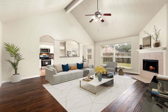 living room featuring beam ceiling, a fireplace, hardwood / wood-style floors, high vaulted ceiling, and ornate columns