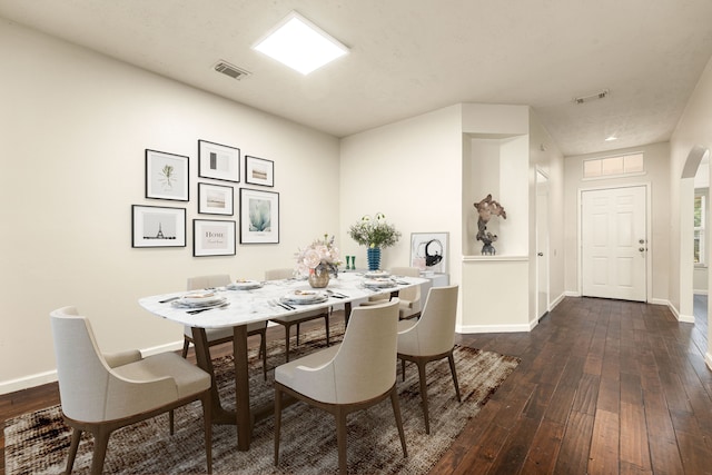 dining area featuring arched walkways, dark wood-style floors, visible vents, and baseboards