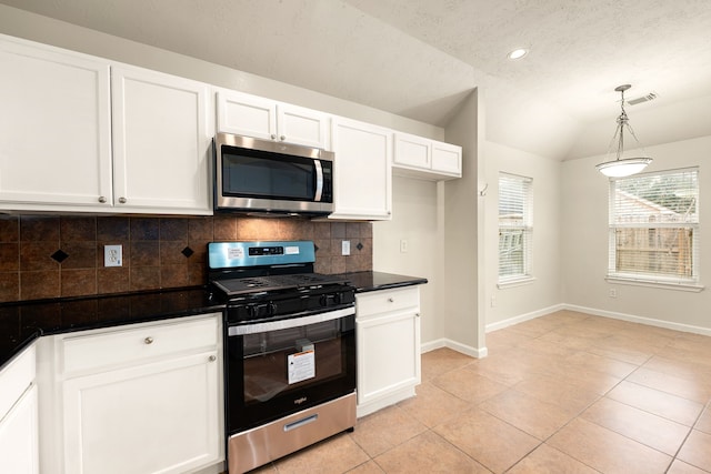 kitchen with tasteful backsplash, dark countertops, appliances with stainless steel finishes, white cabinetry, and vaulted ceiling