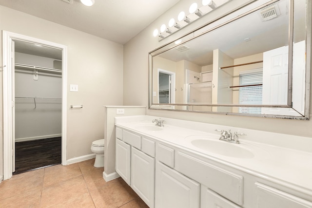 bathroom featuring a spacious closet, a sink, visible vents, and tile patterned floors