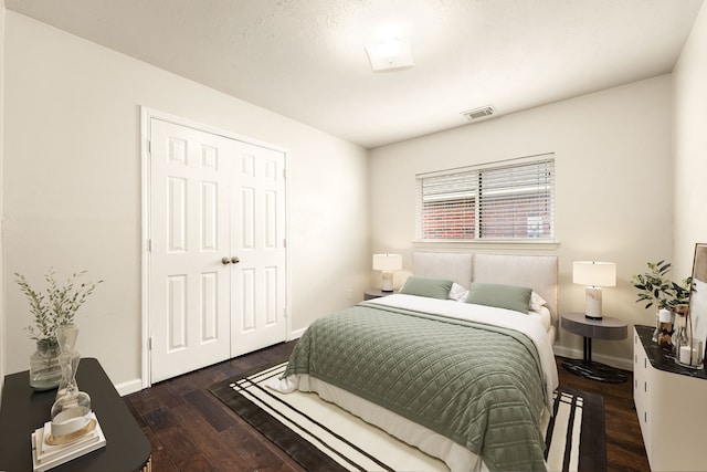 bedroom with dark wood-style floors, visible vents, and baseboards