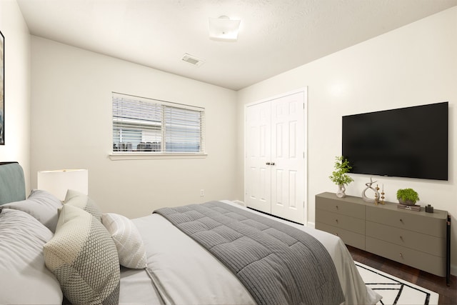 bedroom with dark wood-style floors, a closet, and visible vents