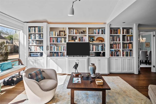 living area with a chandelier, wood finished floors, and crown molding