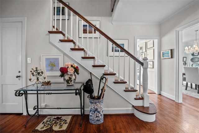 foyer with stairway, an inviting chandelier, ornamental molding, wood finished floors, and baseboards