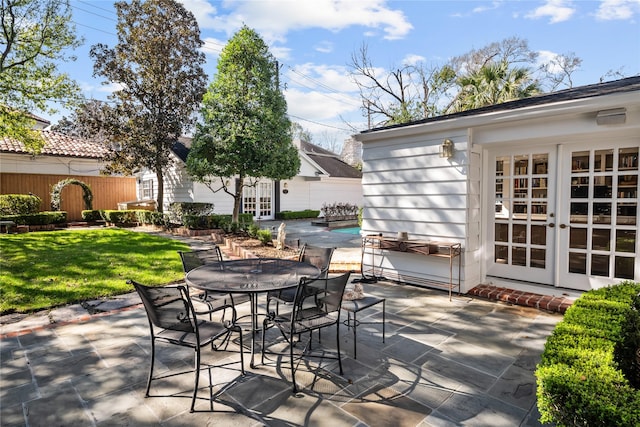 view of patio / terrace featuring outdoor dining space, fence, a fenced in pool, and french doors