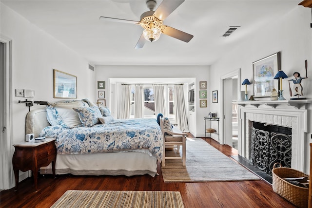 bedroom featuring a fireplace, dark wood finished floors, and visible vents