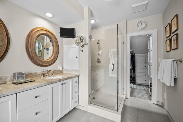 full bathroom featuring a shower stall, a spacious closet, tile patterned flooring, and vanity